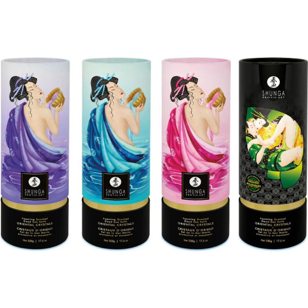 Cristaux de sel de bain bleu vif étalés au premier plan, avec derrière le tube cylindrique de présentation bleu pâle orné d'une illustration de femme aux cheveux noirs et drapé bleu turquoise, logo Shunga et bandeau doré à la base