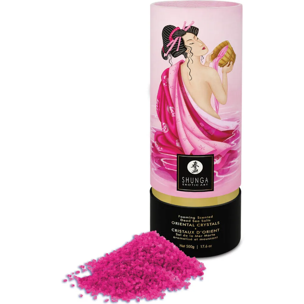 Emballage rose cylindrique de sels de bain Shunga avec illustration d'une femme en drapé rose, accompagné d'un tas de cristaux parfumés rose vif