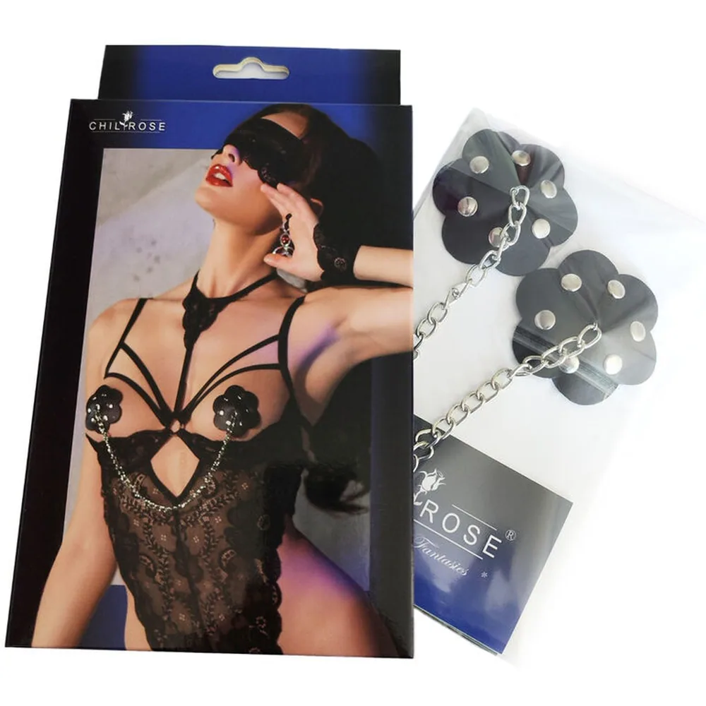 Deux cache-tétons noirs ornés de rivets argentés, reliés par une fine chaîne métallique, posés sur lingerie transparente