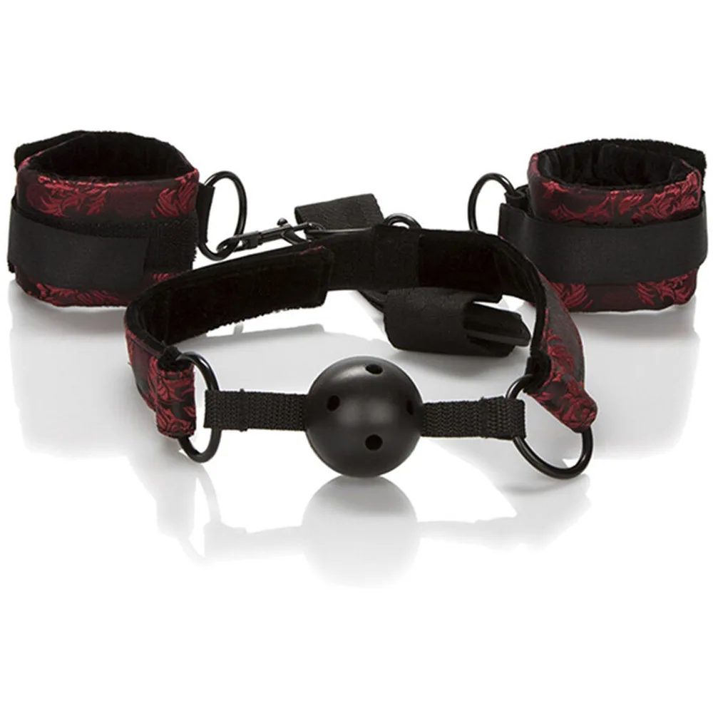 Ensemble composé d'un bâillon boule en silicone noir avec sangle noire, et de deux menottes rembourrées coordonnées noir et motifs bordeaux, reliées par une chaîne noire