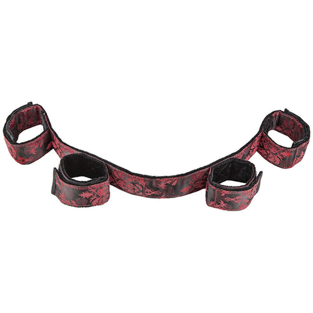 Barre d'écartement avec quatre menottes rembourrées en velours rouge à motif noir, reliées par une barre centrale pliable, sur fond blanc