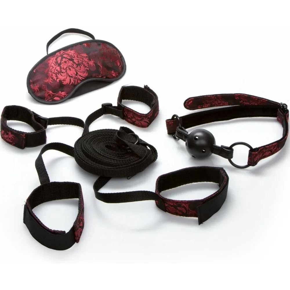 Emballage du kit de retenue pour lit Scandal, montrant une personne portant un masque à paillettes roses et des bracelets de retenue noirs sur un lit blanc, fond bleu