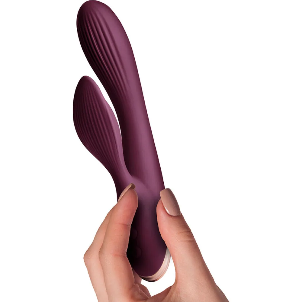 Vibromasseur rabbit en silicone prune avec tige principale courbée nervurée et bras de lapin secondaire, embout rose clair visible sur le côté, sur fond blanc