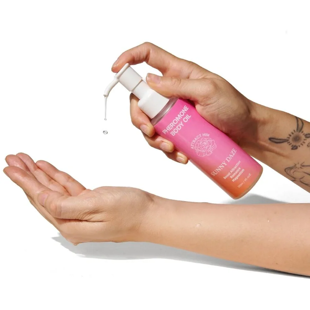 Flacon de 120 ml d'huile corporelle rose et orange avec pompe blanche, étiquette rose dégradée vers abricot indiquant « Pheromone Body Oil » et « Sunny Daze »