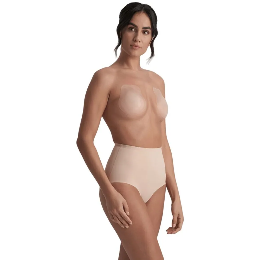 Femme portant un ensemble de lingerie composé d'un haut à bonnets silicone beige clair et d'une culotte assortie, sur fond blanc uni