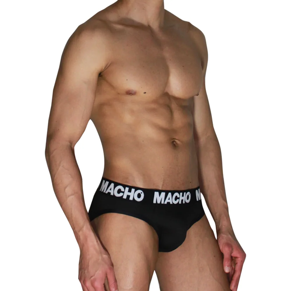 Slip noir porté, ceinture élastique blanche à rayures avec texte « MACHO », taille ajustée pour discrétion sous vêtements